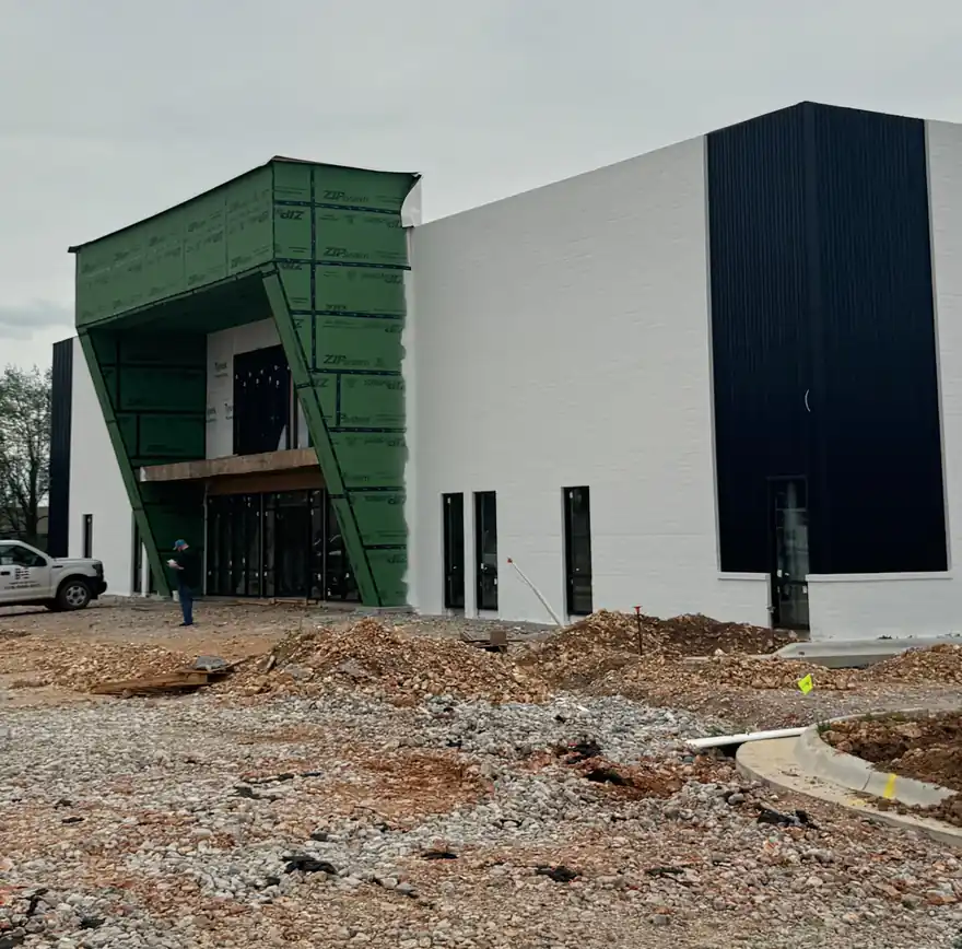 Commercial building under construction with a green panel entry, roof deck ready for the next phase